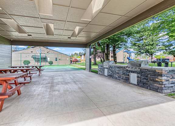 A covered outdoor area with picnic tables and a stone wall.