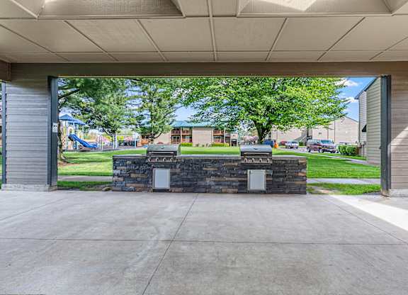 A stone wall with two mailboxes in front of a building.