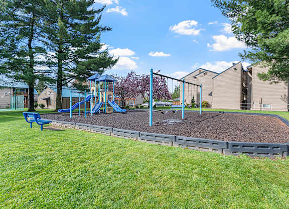 A playground with a slide and a blue bench.
