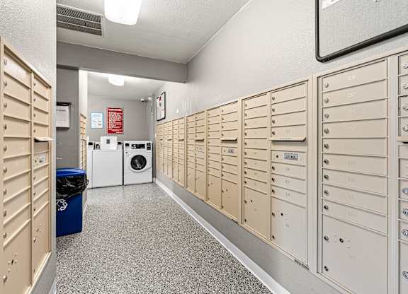 A laundry room with a washer and dryer and a row of mailboxes.