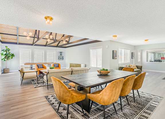 A large room with a table and a room with a shuffleboard table in the background