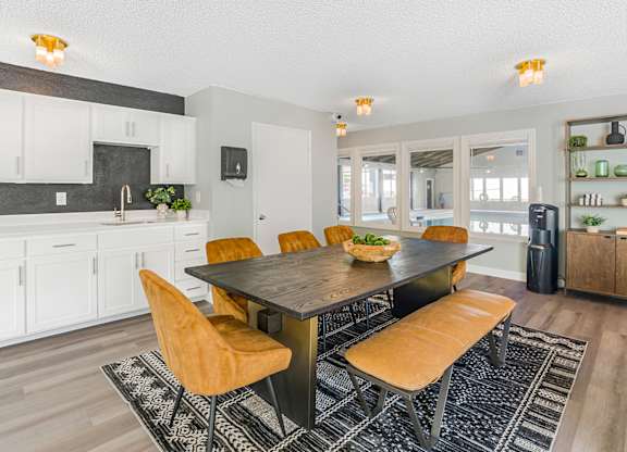 A room with cabinets in the back and a wooden table and chairs.