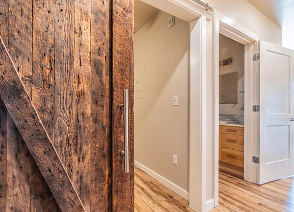 Rustic barn door with modern hallway entrance at Brooklyn Yard Apartments, Portland