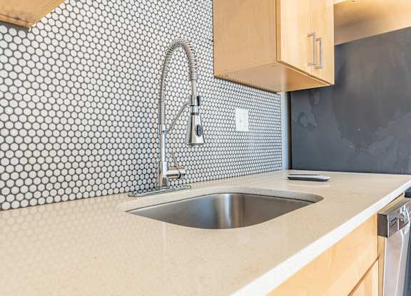 Kitchen sink with penny tile backsplash and modern faucet at Brooklyn Yard Apartments, Portland, OR