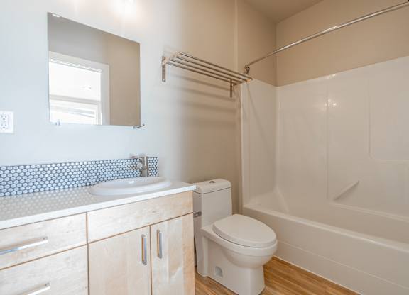 Modern bathroom with light wood vanity and tub at Brooklyn Yard Apartments, Portland, OR