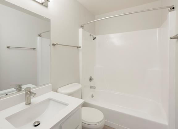 A white bathroom with a sink, toilet, and bathtub.