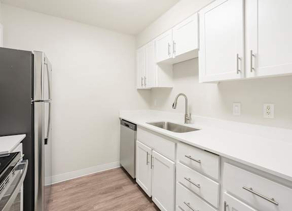 A kitchen with white cabinets and a black refrigerator.