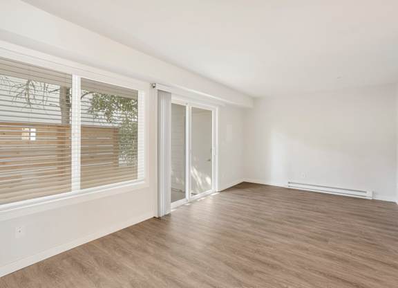 A room with a sliding glass door and wooden flooring.