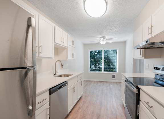 A kitchen with a refrigerator, dishwasher, and oven.