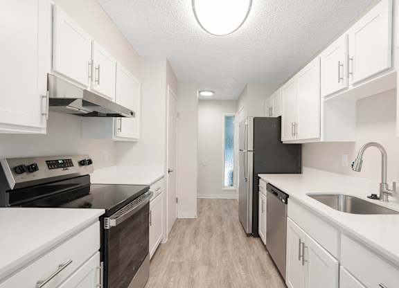 A kitchen with white cabinets and black appliances.