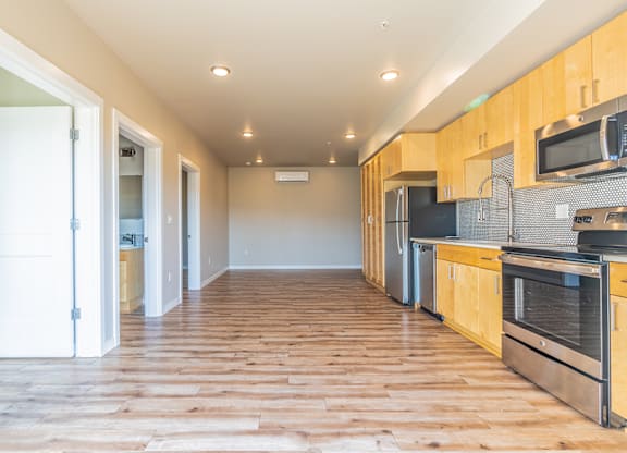 Open floor plan with wood flooring and modern kitchen at Brooklyn Yard Apartments, Portland, OR