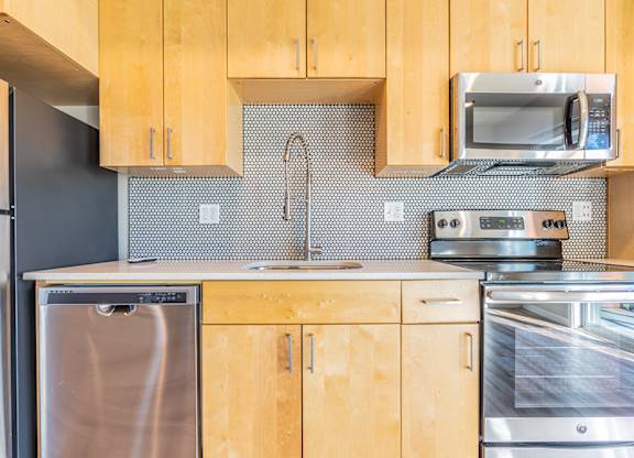Kitchen with penny tile backsplash and modern range at Brooklyn Yard Apartments, Oregon, 97202