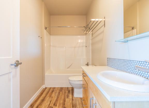 Bathroom with glass shower and penny tile backsplash at Brooklyn Yard Apartments, Portland, OR