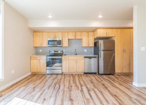 Kitchen with light wood cabinetry and metallic backsplash at Brooklyn Yard Apartments, Oregon, 97202