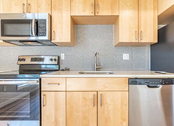 Contemporary kitchen with penny round tile and light wood cabinetry at Brooklyn Yard Apartments, Portland, OR 97202