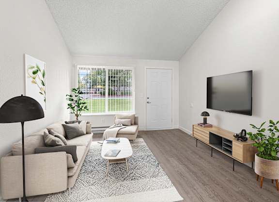 A living room with a grey couch, a black floor lamp, a white door, a grey rug, a wooden coffee table, a flat screen TV, and a plant.