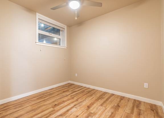 Empty bedroom with window and hardwood flooring at Brooklyn Yard Apartments, Portland, Oregon