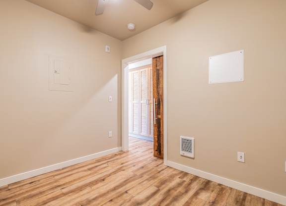 Empty room with rustic wood door accent and ceiling fan at Brooklyn Yard Apartments, Portland