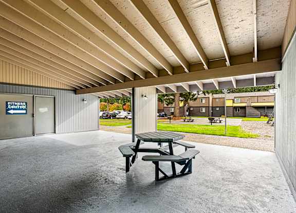 A picnic table sits under a covered patio area.