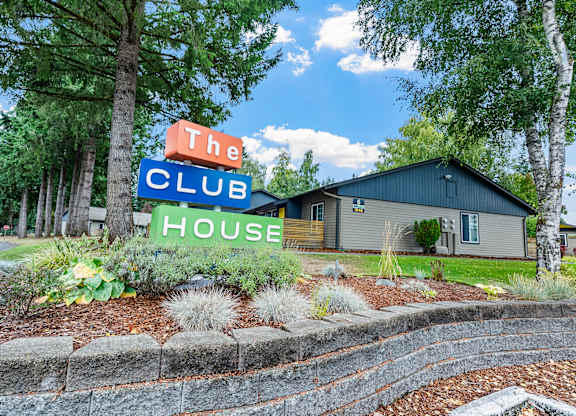 A sign that says The Club House is in front of a building.
