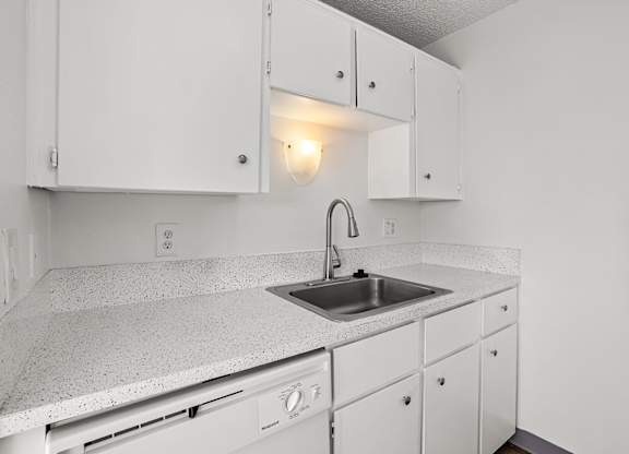 A kitchen with white cabinets and a granite countertop.
