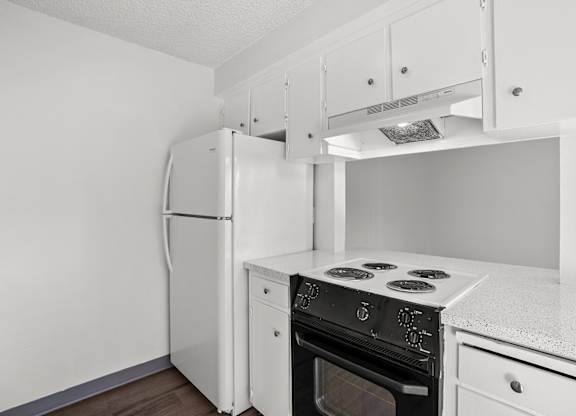 A white kitchen with a refrigerator, oven, and stove.