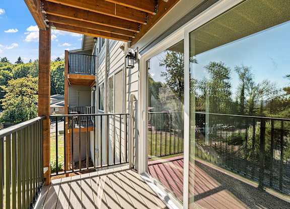 A balcony with a glass door and a wooden railing.