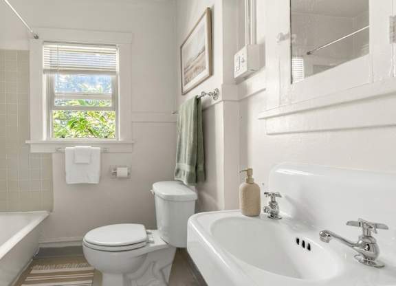 A white bathroom with a toilet, sink, and bathtub.
