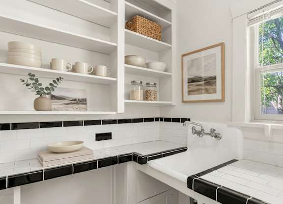 A white bathroom with a window and a sink.