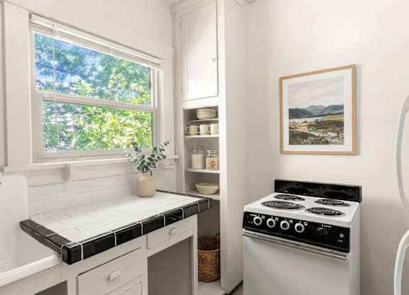 A small kitchen with a stove, sink, and window.