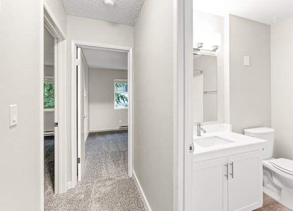A bathroom with a toilet, sink, and mirror.