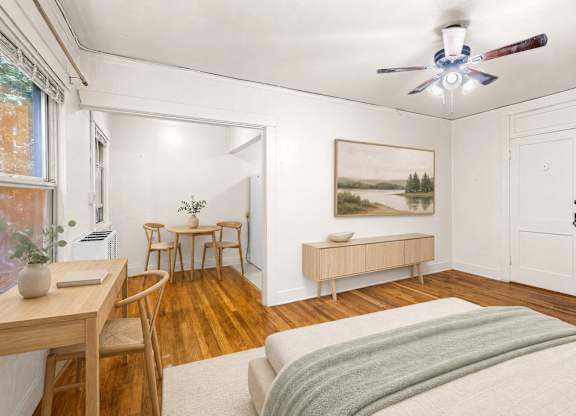 A bedroom with a bed, a table, chairs, and a painting on the wall.