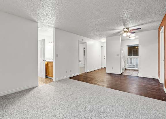 A spacious room with a carpeted floor and a ceiling fan.