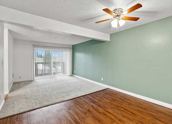 A room with a ceiling fan and sliding glass doors.
