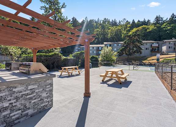A wooden pergola with picnic tables underneath it.