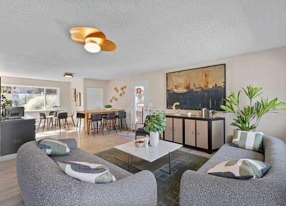 A living room with grey couches and a painting on the wall.