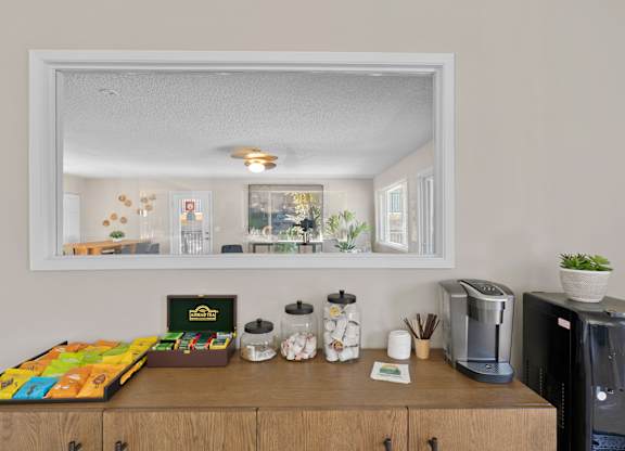 A coffee table with a variety of snacks and a coffee maker on a wooden cabinet.