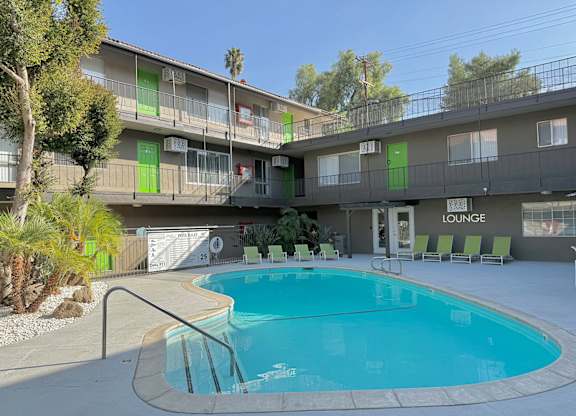 A pool in front of a lounge area with a building in the background.