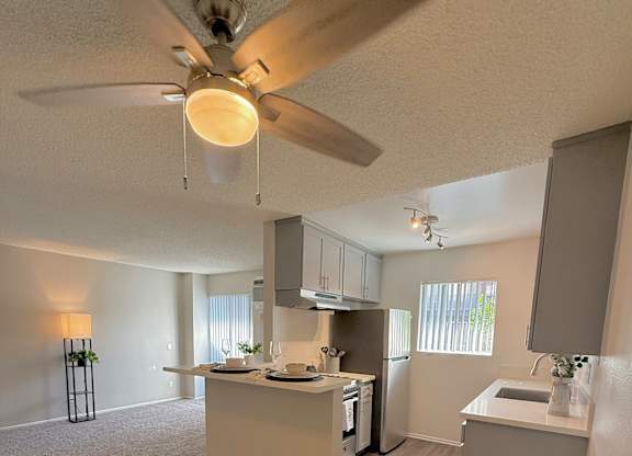 A kitchen with a ceiling fan and a countertop with a sink.
