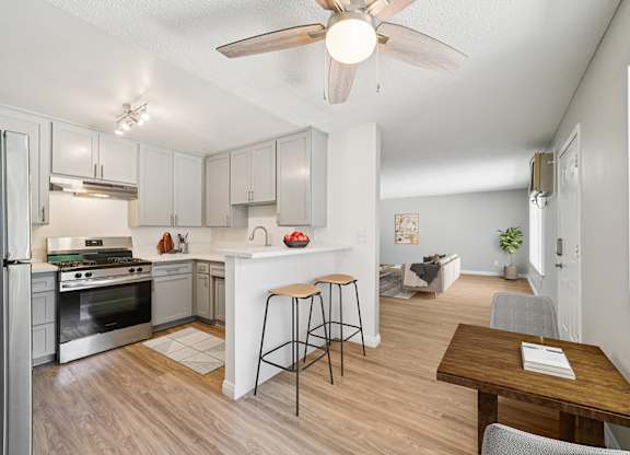 A kitchen with a refrigerator, stove, and bar stools.