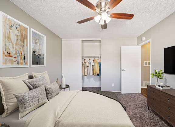 A bedroom with a large bed, a ceiling fan, and a television.