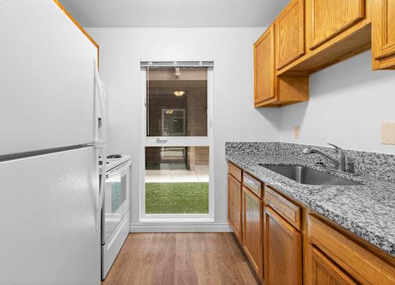 A kitchen with a white refrigerator and wooden cabinets.at East Wind, Gresham, 97030