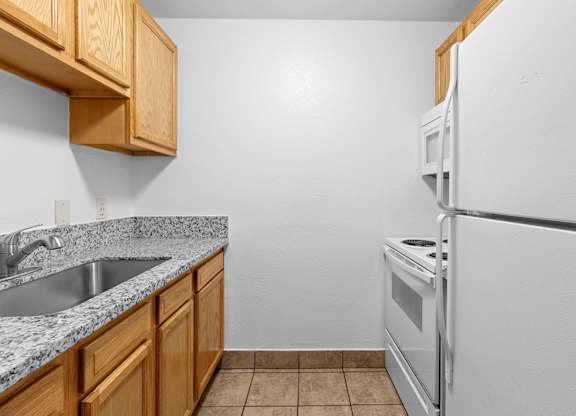 A kitchen with a white refrigerator, sink, and wooden cabinets.at East Wind, Oregon
