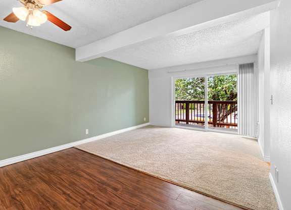 A room with a ceiling fan and sliding glass doors leading to a balcony.at East Wind, Gresham