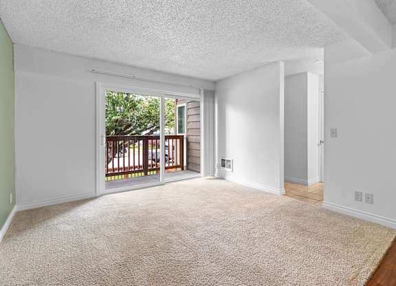 A room with a carpeted floor and a sliding glass door leading to a deck.at East Wind, Gresham, OR