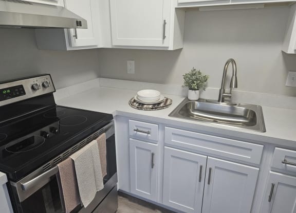 a kitchen with white cabinets and an electric stove and sink