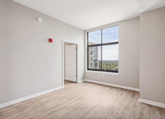an empty living room with a large window and wood flooring