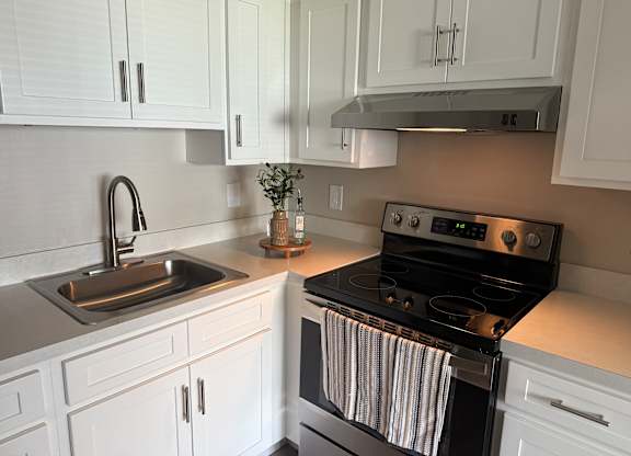 A modern kitchen with white cabinets and a black stove.