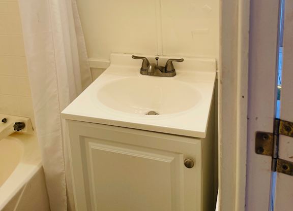A white sink in a small bathroom with a wooden framed mirror above it.