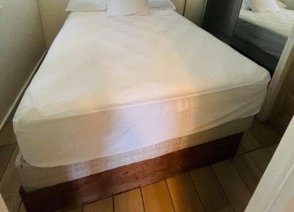 A bed with white bedspread and pillows in a room.